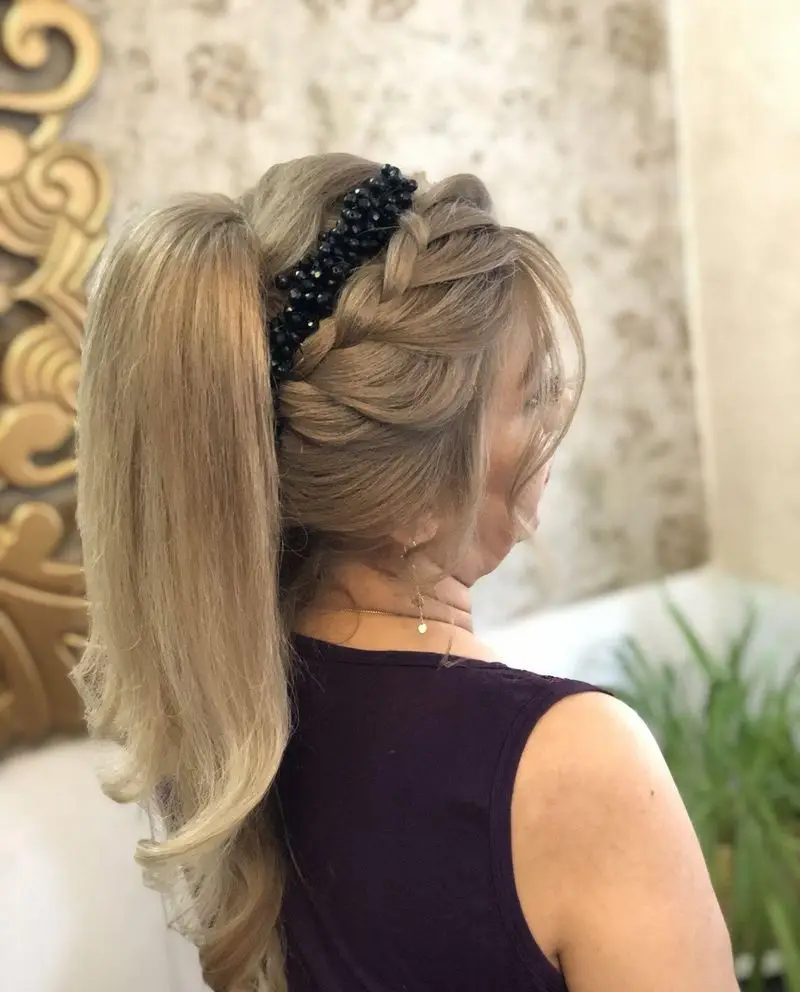 عکس مدل موی دم اسبی مجلسی و شیک دخترانه همراه با بافت موی بغل سر و اکسسوری مشکی مرواریدی روی موهای بلوند روشن در سالن زیبایی