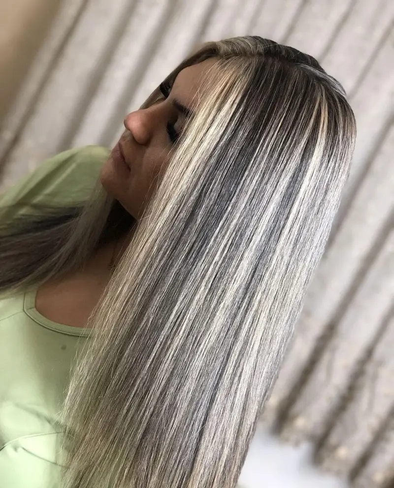 نمای جانبی موهای بلند و صاف زنانه با رنگ و هایلایت تکهای بلوند نقرهای روی زمینه تیره اجرا شده در سالن زیبایی پدیده نو