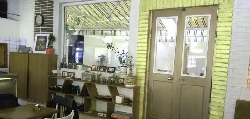 تصویری از محیط داخلی کافی شاپ آلوارس با طراحی مدرن و دلنشین، دارای پنجره بزرگ، قفسه‌های هنری و مبلمان راحت.