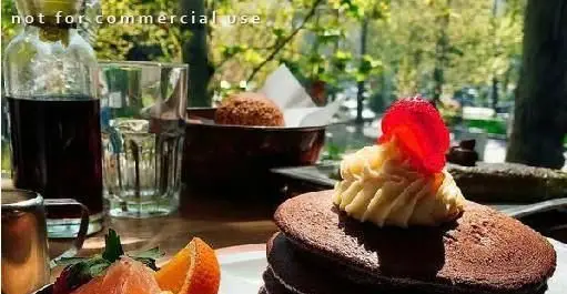 صبحانه‌ای دلپذیر در رستوران فرنگی سبوس: پنکیک‌های شکلاتی با خامه، توت فرنگی، میوه‌های تازه و نوشیدنی‌ها در فضایی دنج و سبز.