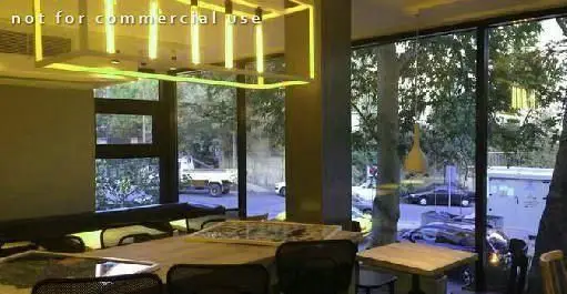 دکوراسیون شیک و روشن رستوران فرنگی سبوس، با میزهای چوبی و چشم‌انداز زیبای درختان و خیابان شهر از پنجره‌های بزرگ.