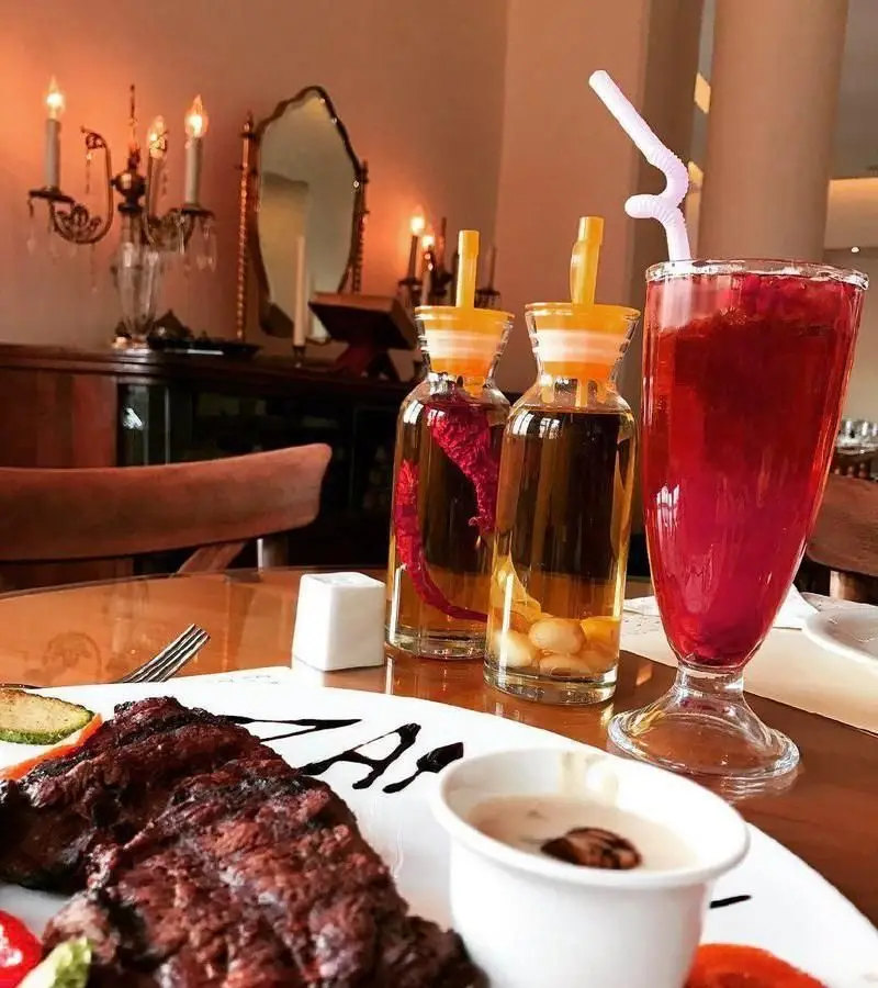 تصویری جذاب از استیک لذیذ، نوشیدنی‌های خاص و فضای سنتی خانه فرهنگ ماه. تجربه یک ناهار یا شام دلپذیر در محیطی فرهنگی و آرام.