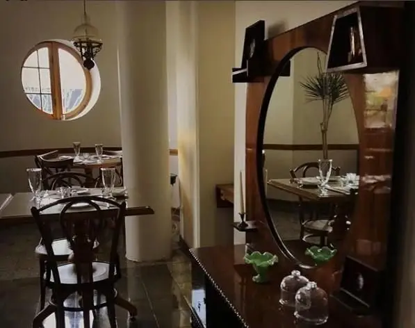 فضای دنج و زیبای کافه و رستوران خانه فرهنگ ماه با پنجره گرد، میز و صندلی‌های چوبی و دکوراسیون سنتی و هنری چشم‌نواز.