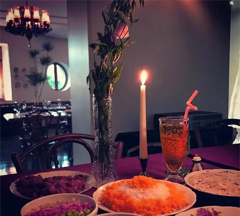 فضای دلنشین خانه فرهنگ ماه: میز شام ایرانی با برنج، خورش، شمع روشن و دکوراسیون گرم رستوران، تجربه‌ای خاص و دنج برای میهمانان.