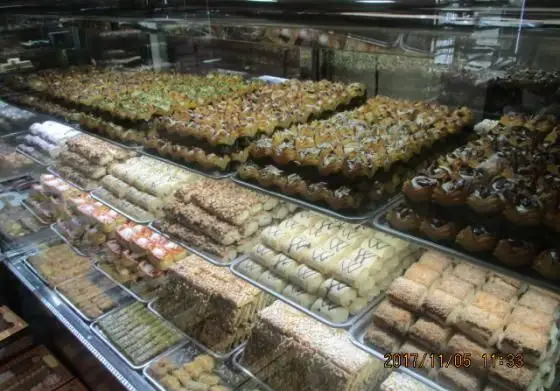 ویترین رنگارنگ شیرینی پدیده شرق با چیدمانی جذاب از انواع باقلوا، شیرینی سنتی و دسرهای خوشمزه تازه و مغزدار.