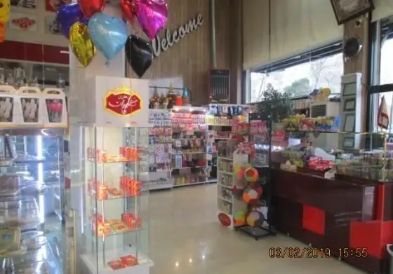 فضای داخلی شیرینی پدیده شرق، یک قنادی مدرن با ویترین‌های پر از دسر، شکلات، شیرینی و محصولات هدیه و جشن، آماده پذیرایی از مشتریان.