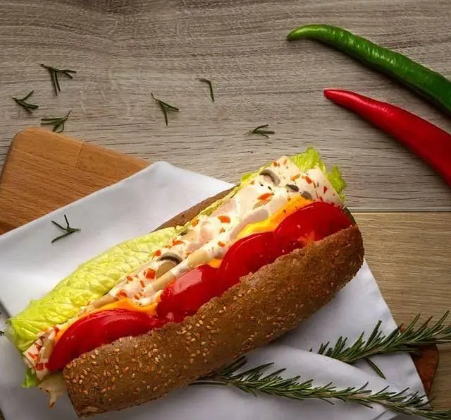 ساندویچ ساب خوشمزه از کافه مارکت با نان کنجدی سبوس‌دار، کاهو، سس، قارچ و گوشت مرغ، همراه با فلفل سبز و قرمز و رزماری.