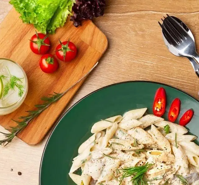 پاستا پنه خامه‌ای با سبزیجات معطر و فلفل در کافه مارکت؛ یک وعده غذایی سالم با مواد اولیه تازه، گوجه، کاهو و نوشیدنی.