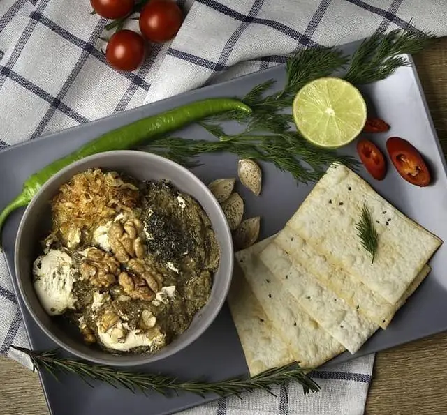 یک کاسه مزه لذیذ شامل مغز گردو و سبزیجات تازه به همراه نان کریسپی، گوجه فرنگی، فلفل و لیمو؛ مناسب کافه مارکت