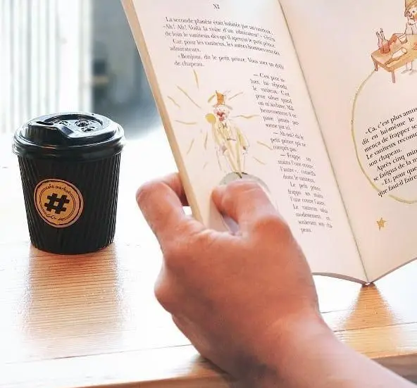 فردی در کافه مارکت در حال لذت بردن از مطالعه کتاب محبوب شازده کوچولو، همراه با فنجان قهوه مخصوص. فضایی دلنشین و آرامش‌بخش برای مشتریان.