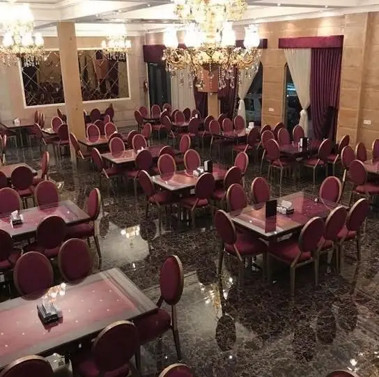 سالن غذاخوری مجلل و شیک رستوران چلو کباب جهان مهر با میز و صندلی‌های قرمز و لوستر‌های درخشان، آماده پذیرایی از میهمانان.