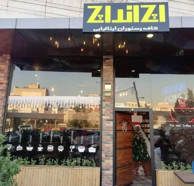 نمای بیرونی کافه رستوران ایتالیایی اچ اند اچ با تابلوی زرد Z&Z، نمایش منوی متنوع شامل پیتزا، پاستا، قهوه و ساندویچ در پنجره.
