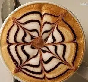 کافه خلبان: لاته آرت پیچیده با طرح تار عنکبوتی و خطوط شکلاتی روی فوم سفید قهوه. نوشیدنی گرم و هنری برای شما.