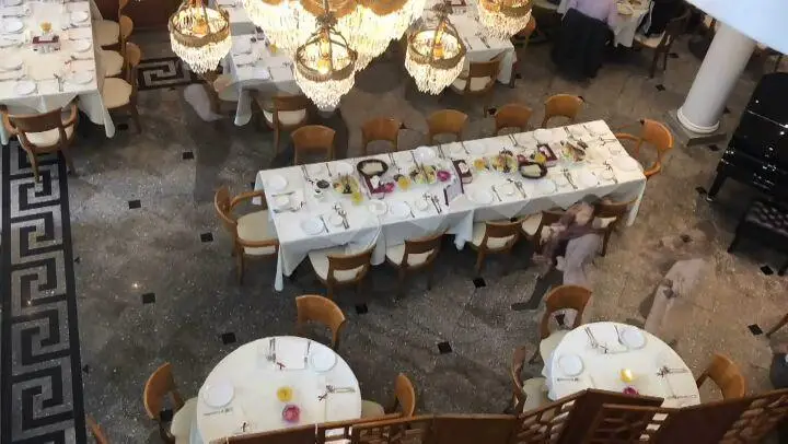 نمای هوایی رستوران نایب ساعی: فضای داخلی مجلل با میزهای چیدمان شده، از جمله میز سلف سرویس، صندلی‌های شیک و لوسترهای دیدنی.