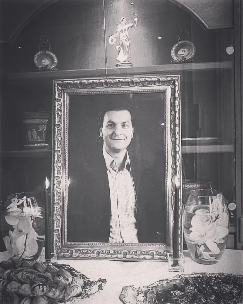 پرتره مردی با لبخند در قاب طلایی، بخشی از دکوراسیون شیک رستوران نایب ساعی تهران، با اشیاء تزئینی و نور شمع، نمادی از تاریخ و اصالت