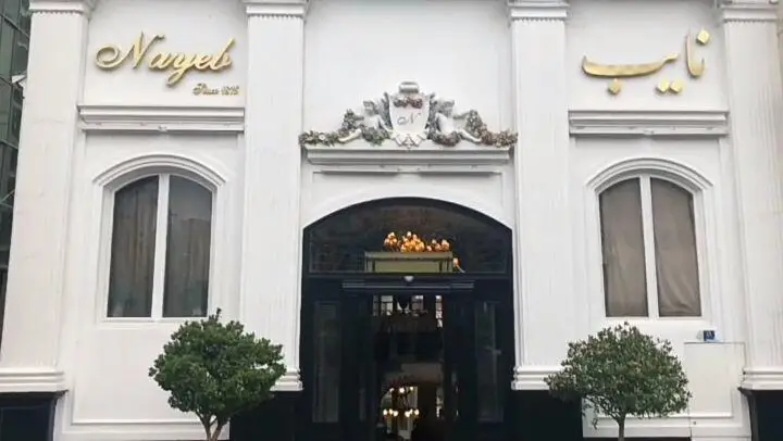 نمای بیرونی شیک رستوران نایب ساعی تهران، با تابلوی طلایی "نايب" و "Nayeb Since 1928" و ورودی مجلل، آماده میزبانی مهمانان.
