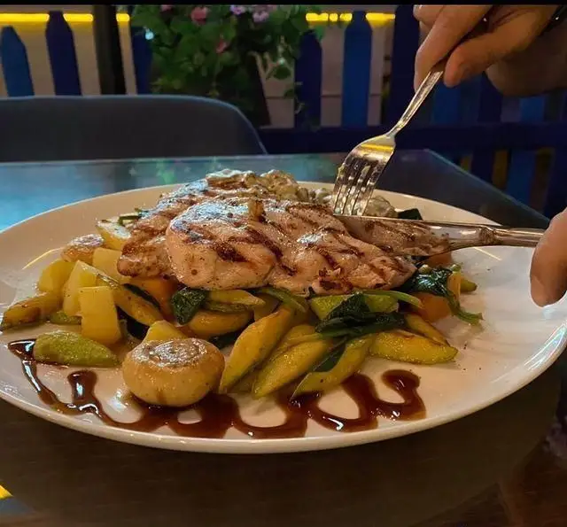 یک بشقاب غذای لذیذ شامل مرغ گریل شده با سبزیجات تازه و سس مخصوص در کافه رستوران ایتالیایی بلوکازا، غذایی سالم و محبوب.