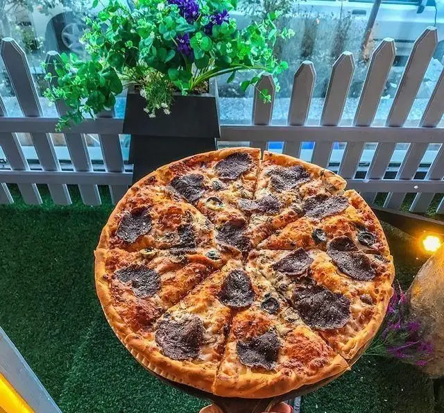 پیتزای لذیذ و پرملات گوشت و زیتون در محیط زیبا و دلنشین کافه رستوران ایتالیایی بلوکازا، مقصدی عالی برای غذای ایتالیایی.