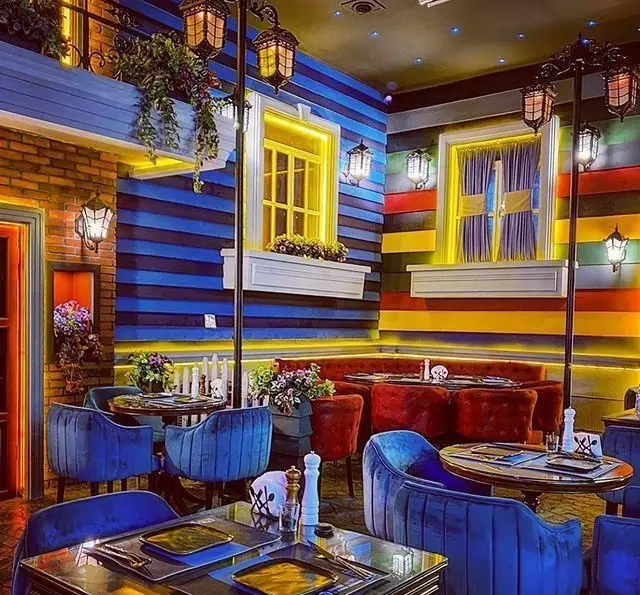 دکوراسیون داخلی کافه رستوران ایتالیایی بلوکازا: فضایی رنگارنگ و دنج با مبلمان مخملی آبی و قرمز، میزهای شیک و نورپردازی گرم
