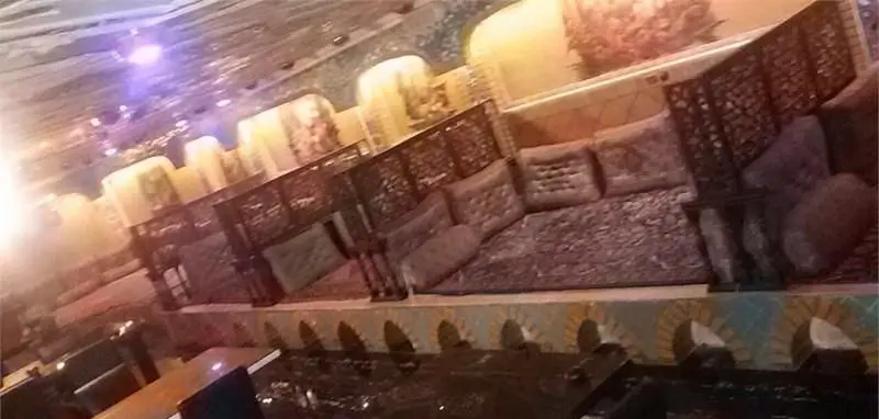 فضای داخلی رستوران فرنگی شاخه طوبی با مبلمان راحت و کوسن‌های طرح‌دار، دیوارکوب‌های سنتی و نورپردازی گرم، محیطی آرام و دلنشین برای پذیرایی.