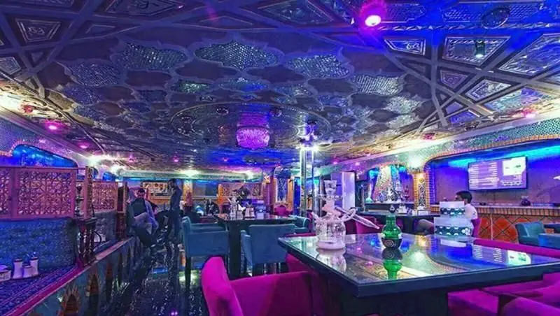 فضای داخلی رستوران فرنگی شاخه طوبی با دکوراسیون لوکس، سقف آینه‌ای، نورپردازی آبی و بنفش، مبلمان مخملی و سرو قلیان.