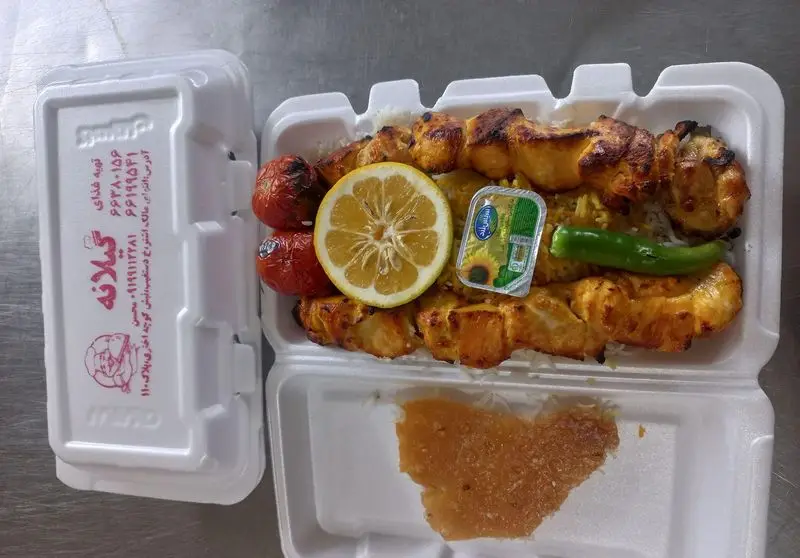 جوجه کباب و برنج ایرانی تهیه غذای گیلانه به همراه گوجه، لیمو و ته دیگ در ظرف بیرون بر؛ غذای آماده و لذیذ ناهار یا شام.