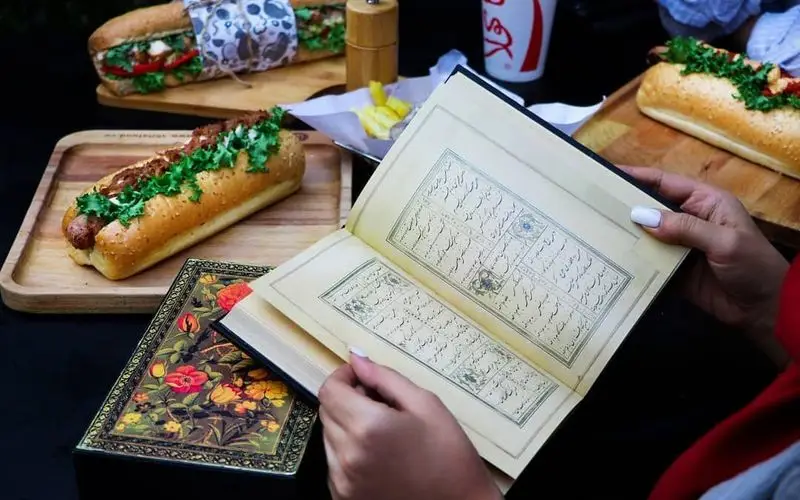 ترکیب دلنشین مطالعه کتاب نفیس و لذت خوردن هات داگ، ساندویچ و سیب زمینی در فضای فست فود شیلا.