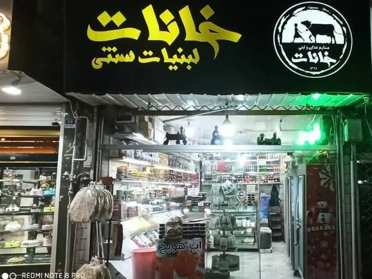 تصویری از نمای بیرونی فروشگاه و مغازه لبنیات سنتی خانات با تابلوی زرد رنگ و محصولات غذایی سنتی و با کیفیت داخلی.