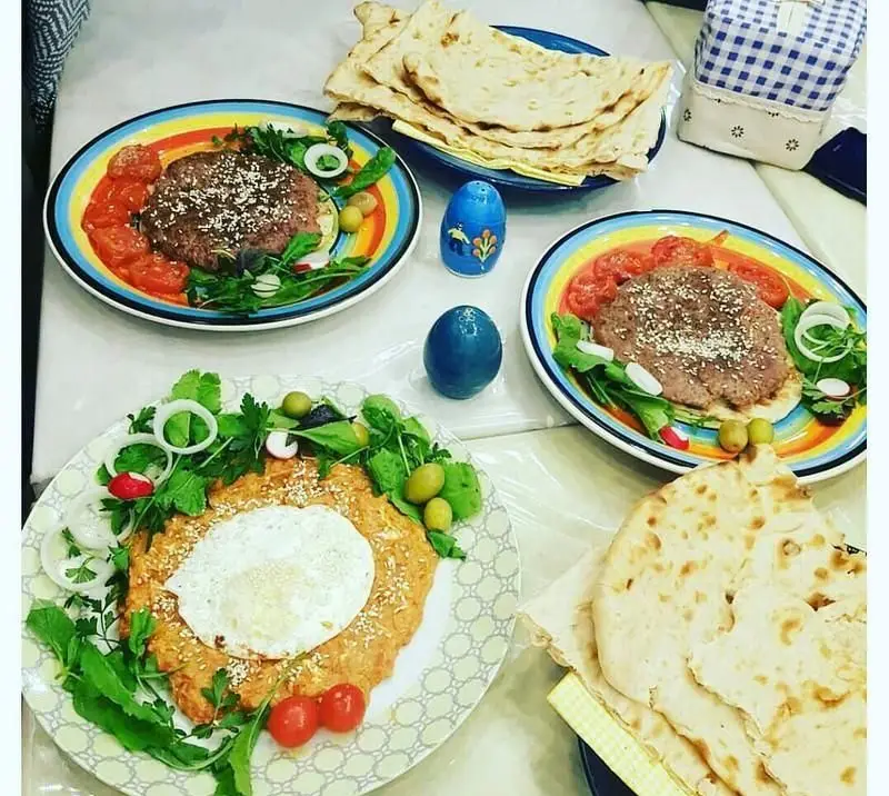 رستوران ایرانی دیزی شاپ: میز شام رنگین با کباب، کشک بادمجان با تخم مرغ، نان تازه و سبزیجات متنوع