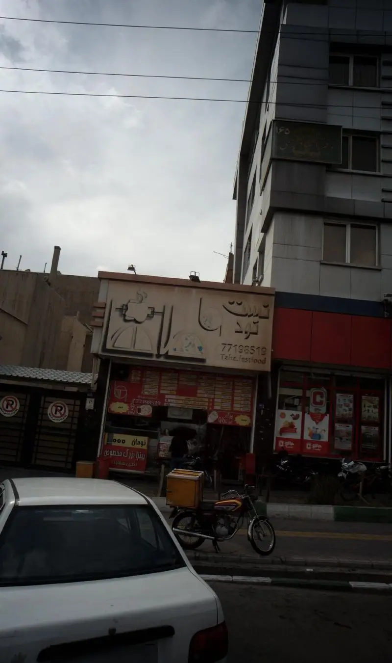 نمای خیابانی از فست فود تازه که به رستوران ۲۵ میل مرتبط است، با موتورسیکلت تحویل در جلوی آن، آماده برای خدمت‌رسانی به مشتریان.