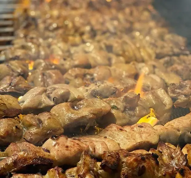 تصویری جذاب از پخت کباب‌های لذیذ در چلو کبابی جوانان پاسداران، گوشت‌های تازه و آبدار در حال گریل شدن روی منقل با شعله آتش.