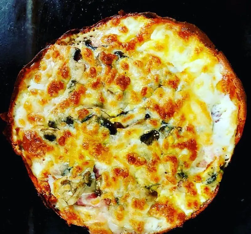 یک پیتزای شخصی یا گراتن پنیر برشته و طلایی فست فود ماموت با قارچ و سبزیجات، آماده سرو و لذت بردن از طعمی بی‌نظیر.