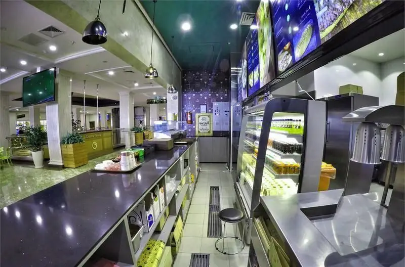 فست فود آلپاچینو: فضای داخلی مدرن و روشن با پیشخوان طولانی، یخچال‌های ویترینی انواع نوشیدنی، نمایشگرهای منو و محیطی دلنشین برای مشتریان.