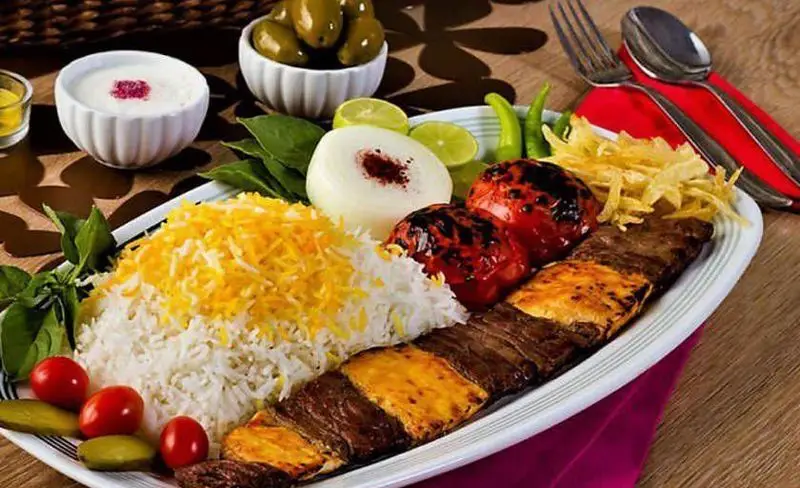 چلوکباب کوبیده و برگ لذیذ رستوران فرصت؛ غذای اصیل ایرانی با برنج زعفرانی، گوجه کبابی، پیاز، ماست و زیتون. لذت آشپزی ایرانی