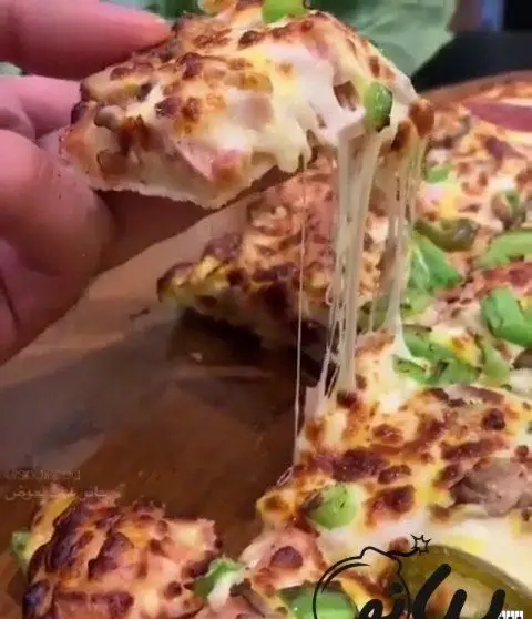 پیتزا داغ و لذیذ فست فود پیانو با پنیر کش‌دار بی‌نظیر، ژامبون، قارچ و فلفل سبز تازه. تجربه‌ای خوشمزه.