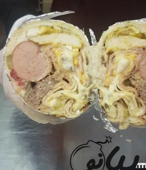 ساندویچ بمب پرملات فست فود پیانو: شامل ژامبون، مرغ، گوشت چرخکرده و پنیر آب شده، یک وعده غول‌پیکر و لذیذ.