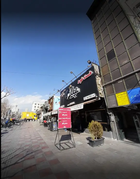 نمای بیرونی فست فود پیانو با تابلوی مشکی، منو و قیمت‌های ویژه، به همراه آدرس 54183.ir در خیابانی پرتردد در تهران.