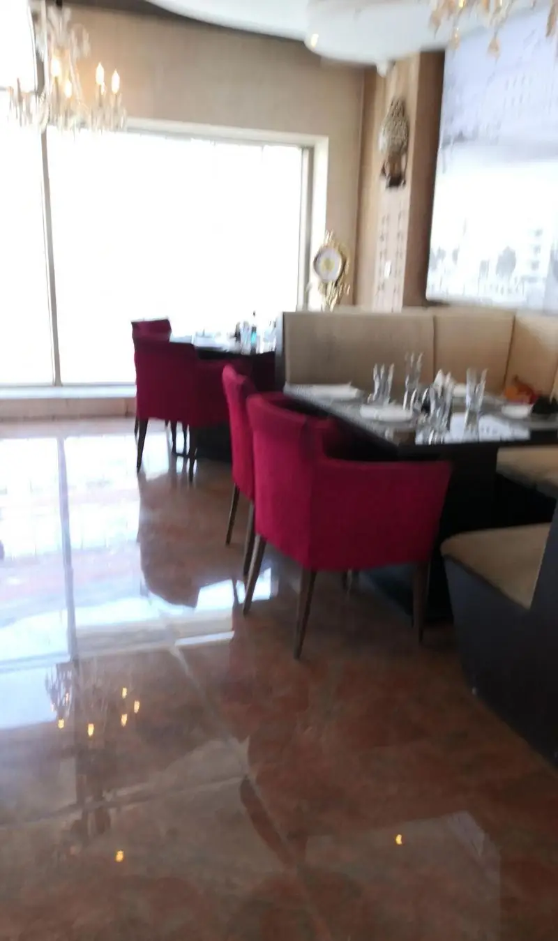 فضای داخلی رستوران تهران پاریس با دکوراسیون مدرن، صندلی‌های قرمز شیک، میزهای مرتب و پنجره‌های بزرگ، محیطی دلنشین برای صرف غذا.