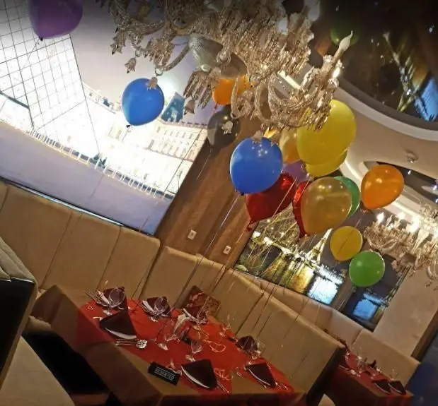 دکوراسیون داخلی لوکس رستوران تهران پاریس، میزآرایی جشن با بالون‌های رنگی و لوسترهای شیک برای مناسبت‌های خاص.