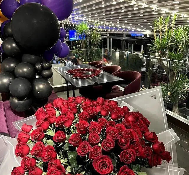 دکوراسیون رمانتیک و زیبای رستوران 10forever با دسته گل رز قرمز بزرگ، بادکنک‌های جشن و میز شام تزئین شده برای لحظات خاص.