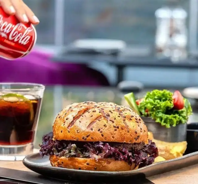 عکس یک برگر لذیذ با نان کنجدی، کاهوی بنفش، سالاد سبز تازه و نوشابه. تجربه طعم بی نظیر در رستوران 10forever.