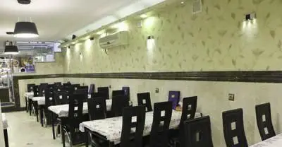 فضای داخلی رستوران ایرانی نشاط با میز و صندلی‌های چوبی تیره و رومیزی‌های سفید، آماده پذیرایی از مشتریان است. دکوراسیون شیک و مدرن.