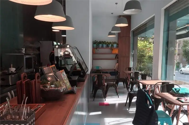 داخلی کافی شاپ بیت بیسترو با فضای مدرن و میز و صندلی، پیشخوان مجهز و نور طبیعی از پنجره‌های بزرگ به سمت خیابان.