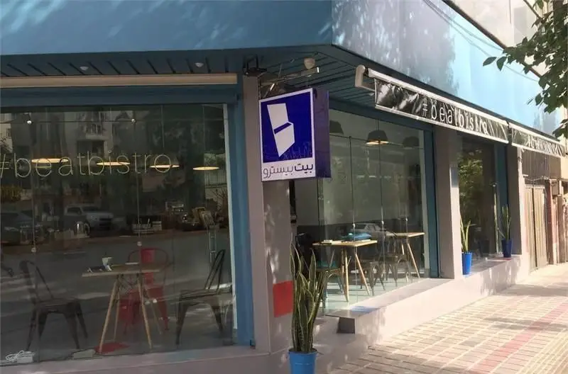 نمای بیرونی دنج و زیبای کافه و کافی شاپ بیت بیسترو با تابلو و نام فارسی. طراحی داخلی و فضای دلنشین از پشت شیشه‌ها پیداست.