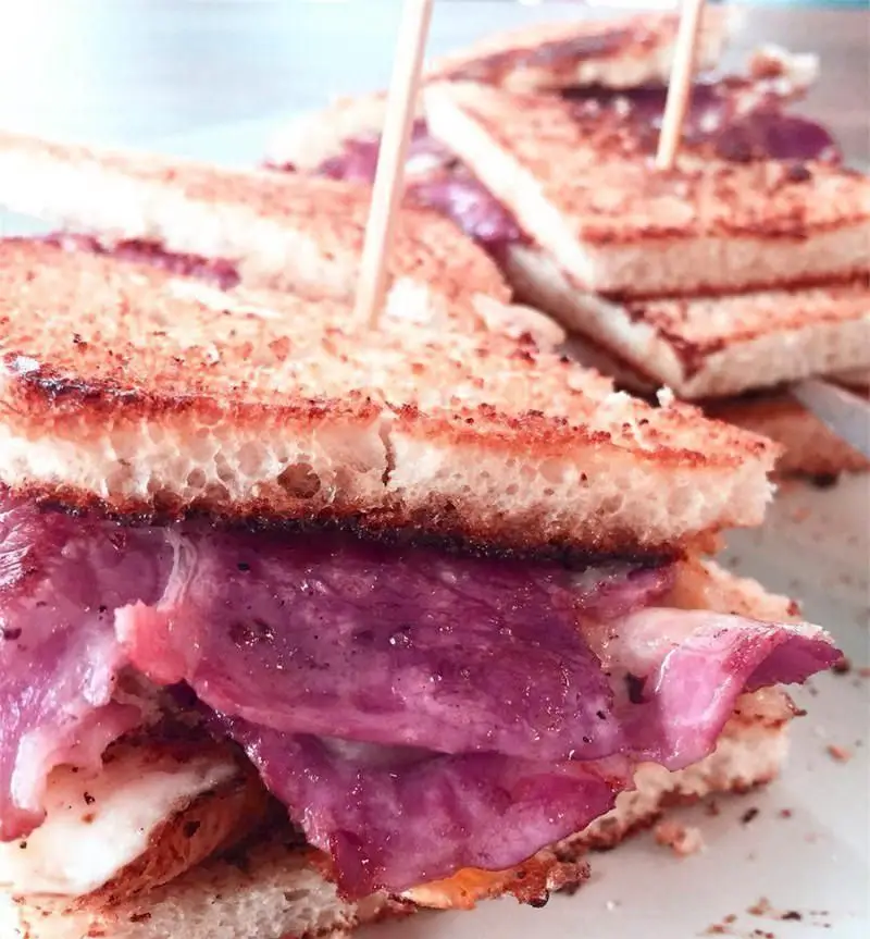 ساندویچ تست ویژه و خوشمزه کافی شاپ بیت بیسترو با نان برشته طلایی و محتویات جذاب بنفش رنگ، تجربه‌ای بی‌نظیر برای هر وعده.