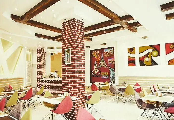 دکوراسیون داخلی مدرن و جذاب رستوران ایتالیایی شادی با میز و صندلی‌های رنگارنگ، سقف چوبی و دیوارهای آجری، فضایی دلنشین برای صرف غذا.