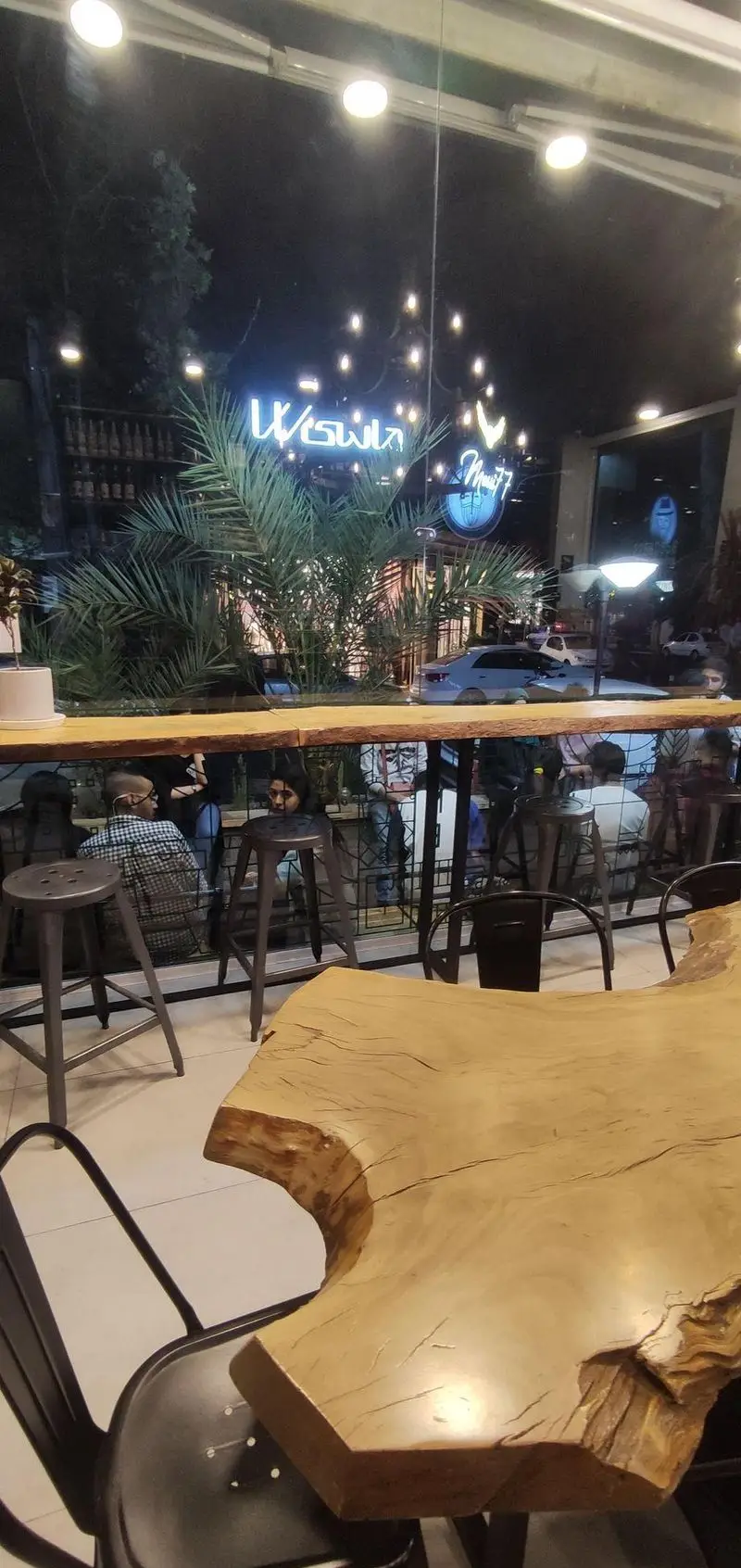 نمای داخلی کافه سربن در شب، با میزهای چوبی زیبا و محیطی دلنشین برای مشتریان. نورپردازی جذاب و فضای بیرونی کافه.