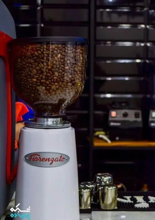 تجهیزات مدرن کافی شاپ قهوه سربن: آسیاب قهوه فیورنزاتو سفید رنگ پر از دانه های مرغوب قهوه، آماده سرو بهترین قهوه.