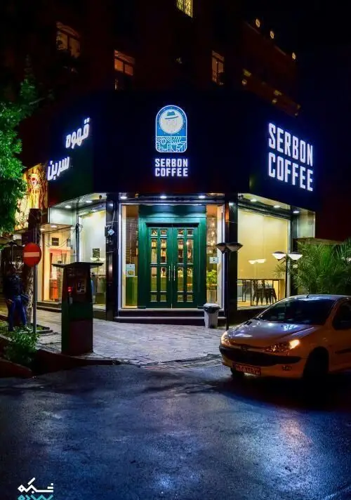 نمای چشمگیر و روشن از کسب و کار قهوه سربن در شب، با لوگو و نام "SERBON COFFEE" بر روی تابلوی نئون و ورودی شیک.