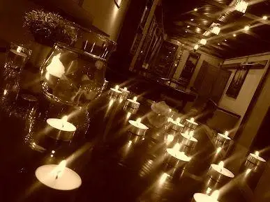 کافه قانون: تصویری دلنشین از فضای داخلی با نورپردازی گرم شمع، محیطی آرام و رمانتیک برای مطالعه یا دورهمی.